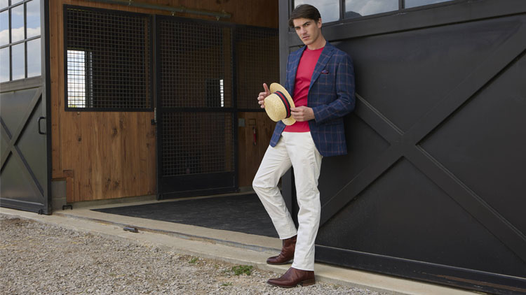Man leaning agains a black barn door wearing the Tony Lama Lenado 12" Western boot in brown.