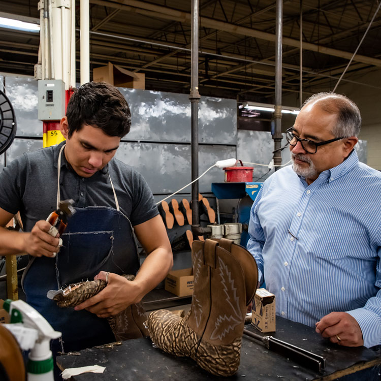 man uses tool on bottom of cowboy boot 