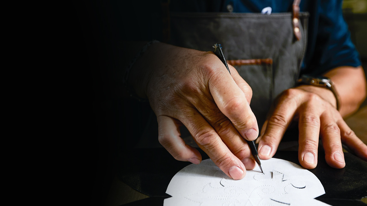 A factory worker cuts a template out of leather.