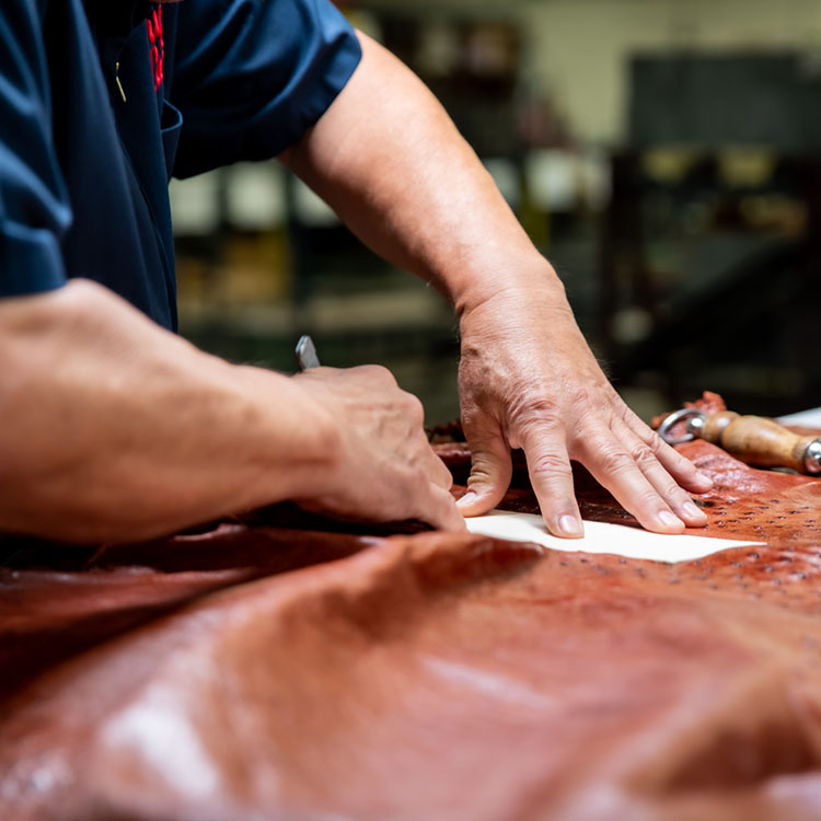 man cuts exotic leather with knife