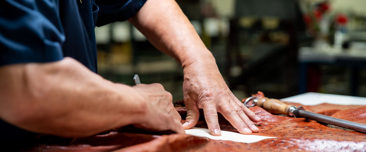 man cuts exotic leather with knife