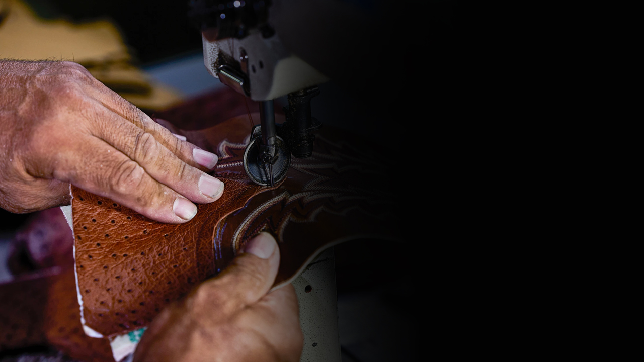 Factory worker stitches thread into a Tony Lama boot.
