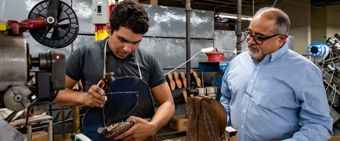 man uses tool on bottom of cowboy boot 