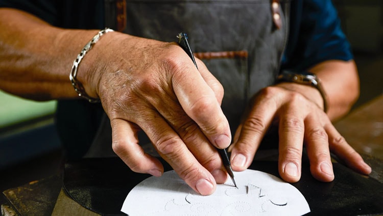 A factory worker cuts a template out of leather.