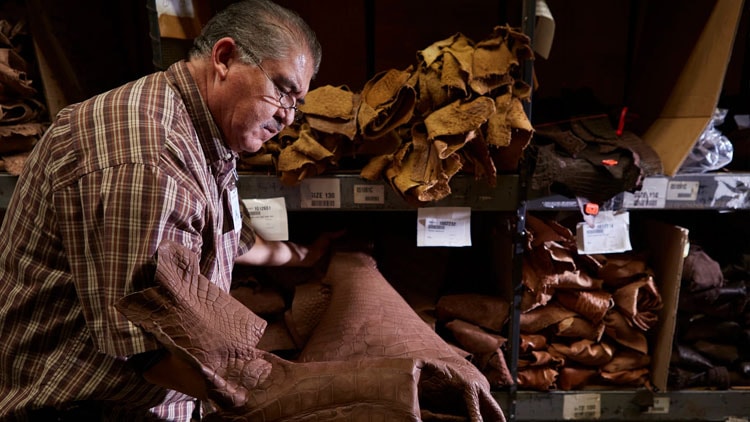 A factory worker examines leather on the factory floor.