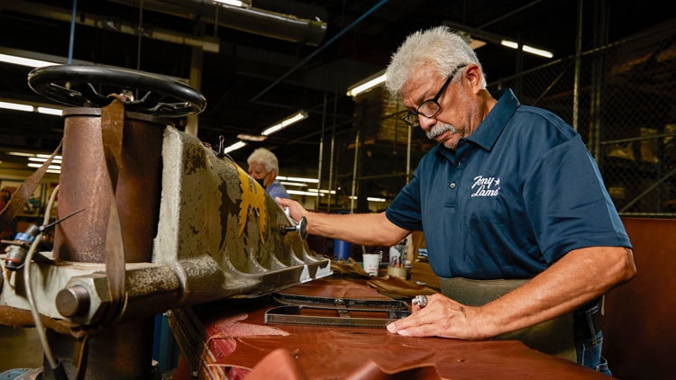 Factory worker stamps a template for boot out of leather.