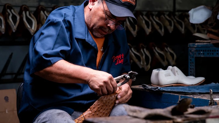 Factory worker stretches leather over a last for a Tony Lama boot.