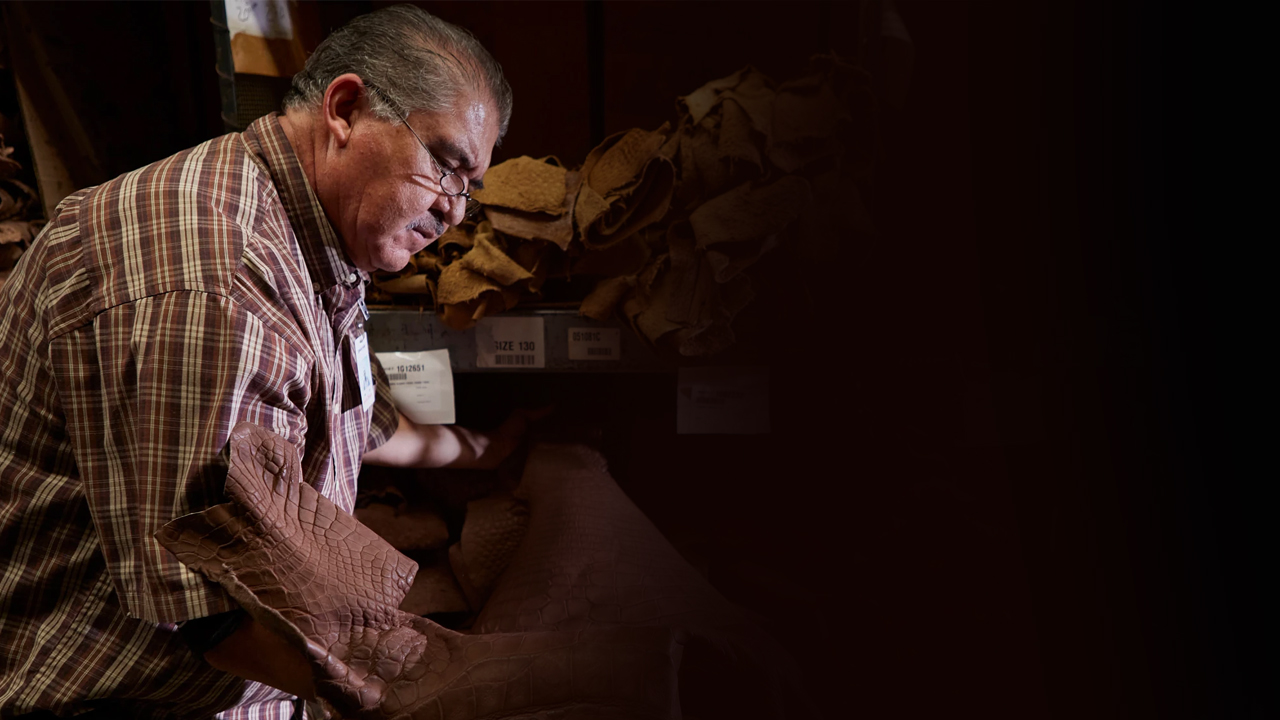 A factory worker examines leather on the factory floor.
